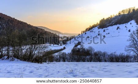 Cold snowy winter sunset in Bavaria, Germany. Sweet Solitude. White and Lonely hill Landscape. Lovely orange sunset