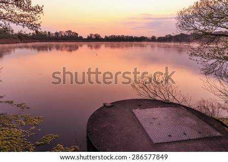 Serene Sunrise at the Lake. Spring Dawn. Lovely colors. Tree Silhouettes and warm water in Bavaria, Germany
