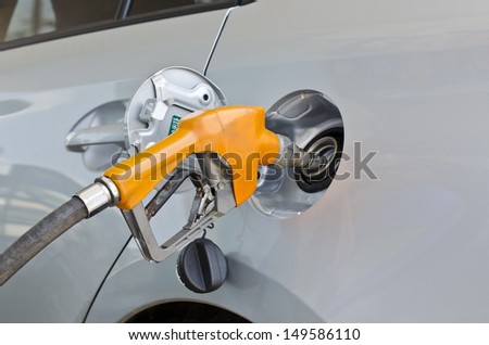 Grey car at gas station being filled with fuel