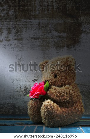 Still life of cute bear doll holding rose bouquet