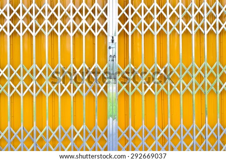 Yellow metal grille sliding door with pad lock and aluminum handle