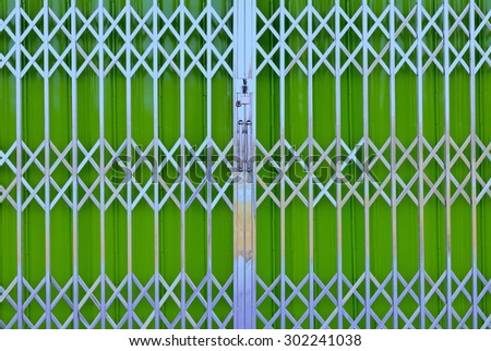 Green  metal grille sliding door with pad lock and aluminum handle