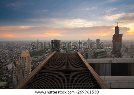 Bangkok city sunset view from rooftop of skyscraper building with steel grate floor