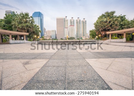 Tiles floor pavement plaza in Bangkok city Benchakitti Park with modern office building background in the evening