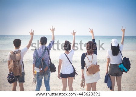 A group of five young teenager friends travel to the beach looking at the sea