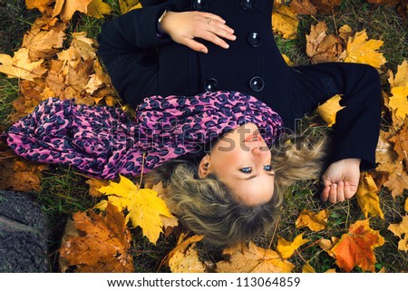 beautiful girl in scarf lying under autumn tree