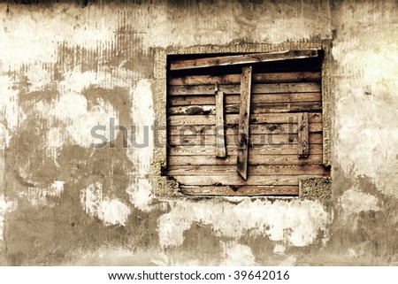 wall of a deserted house with boarded up window