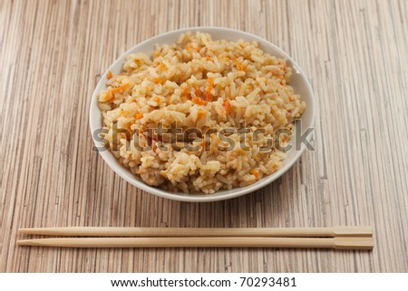 bowl of cooked rice with chopsticks on the bamboo textured table
