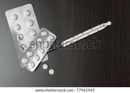 medicine and thermometer on brown table