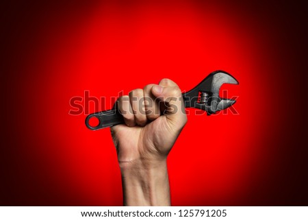 man holding adjustable wrench over red background