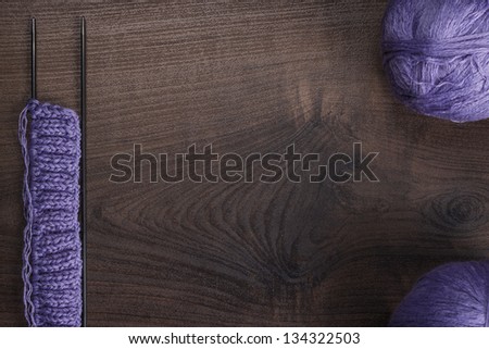 knitting needles and balls of threads on wooden background