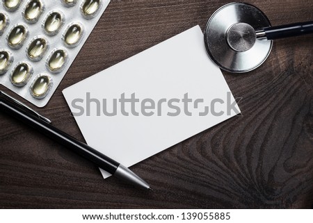 blank notebook statoscope and pills on the dark brown wooden table