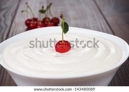 white bowl full of sour cream with cherry on top