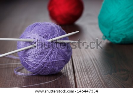 knitting needles and balls of threads on the wooden table