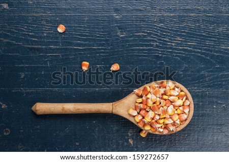 old wooden spoon full of dry corn on the blue table