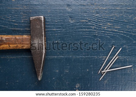 old hammer and nails on blue wooden background
