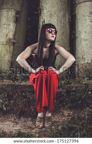 girl in red pants and glasses on industrial background