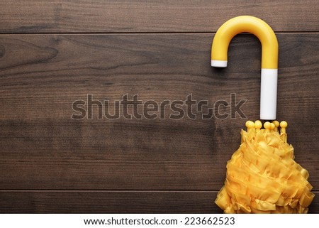 folded yellow umbrella on the brown background