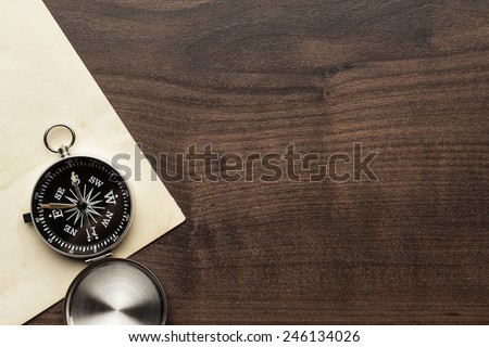 compass and old paper on the brown wooden table background