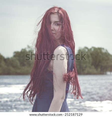beautiful red-haired woman standing in the river