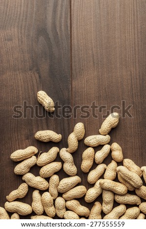 many roasted peanuts on the wooden table background