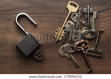 opened check-lock and different keys on wooden background concept