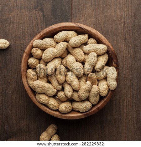 many roasted peanuts in wooden bowl on the table background