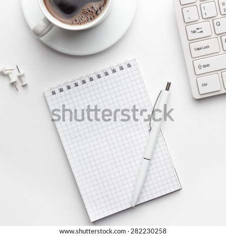 view from above on white office table with notepad, computer and coffee cup