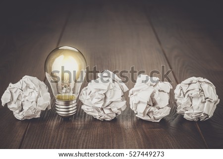 great idea concept with crumpled office paper and light bulb standing on table