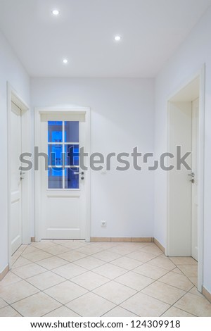 Indoor Foyer With White Doors, Light Brown Tiled Floor, Lamps