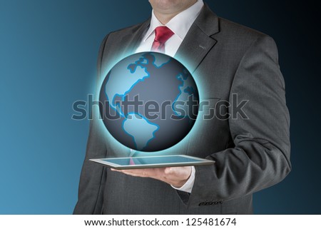 Well dressed business man is holding a tablet computer that is showing an illustration of the earth. Background is blue / black.
