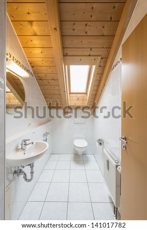 Picture of a white tiled restroom with basin, toilet, mirror, light and window