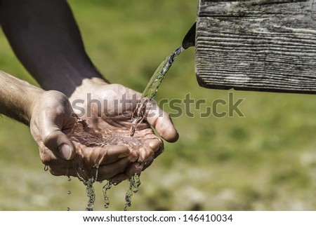 Thirsty Hands taking water from a well in the Alps