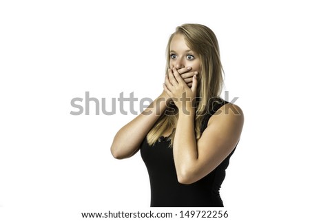 Shocked young girl in black shirt who is afraid and keeps up with eyes wide open hand over her mouth, isolated on white background