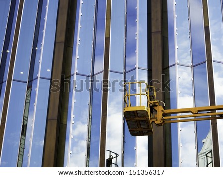 Crane with basket with nobody in front of a modern glass facade