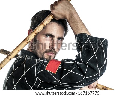 Martial arts master with black combat dress and two short bamboo sticks, isolated on white background
