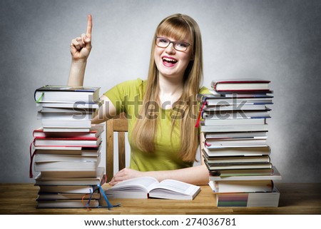 young happy student woman with glasses and lots of books at a table