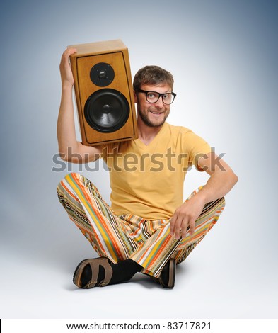Cool dude in color striped trousers with wooden hi-fi speaker, sound concept