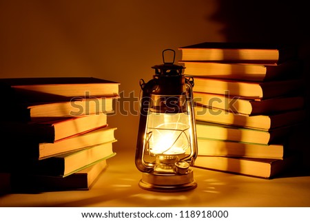 Burning kerosene lamp and books, concept magic of light