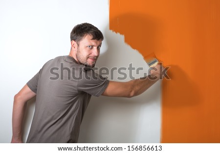 Bearded man paints the white wall