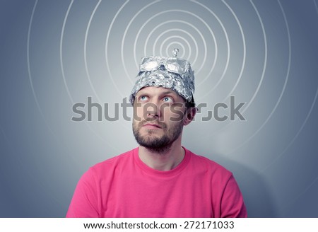 Bearded funny man in a cap of aluminum foil sends signals. Concept art phobias