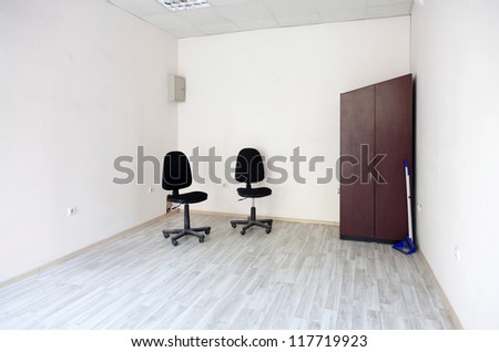 Two chairs and a wardrobe in an empty office room