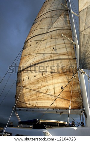 The main sail on a catamaran, lit by early morning sunlight.