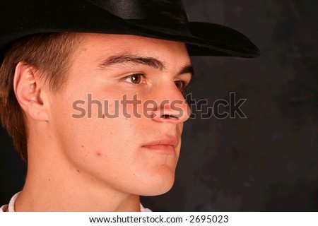 Close Up of young male model in cowboy hat  on a black background.