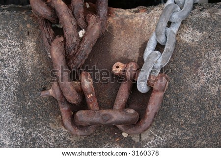 Old rusty chains fixed to a concrete block shot from above.