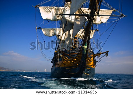HMS Surprise Sailing Ship at Sea under full sail with tall ships in the background.