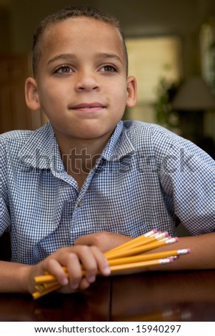 young boy looking off camera while waiting, holding pencils