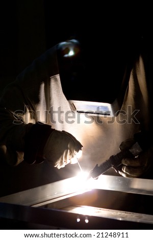 professional craftsman welding metal materials with safety helmet and gloves