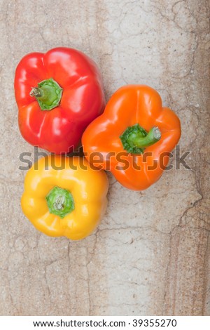 Bird\'s eye view of three bell peppers sitting on cutting board.