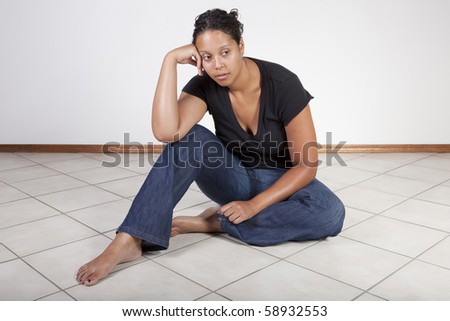 Frustrated black woman sitting on floor, contemplative.